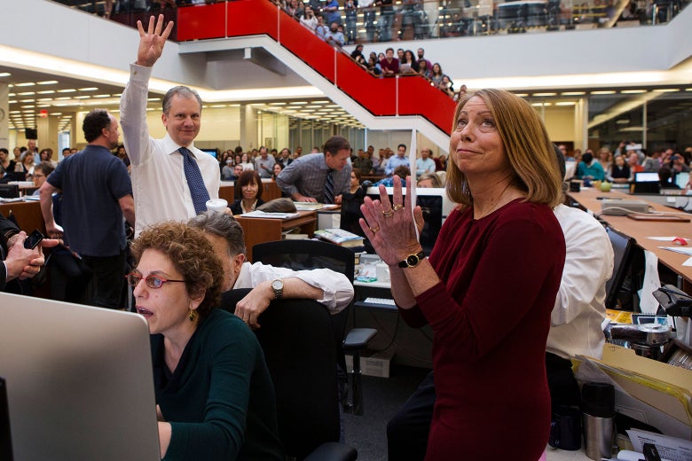 Staffers crowded in the New York Times newsroom as Pulitzer Prize winners are announced. Abramson looks up, clapping. Arthur Sulzberger Jr. holds up four fingers to signify four wins.